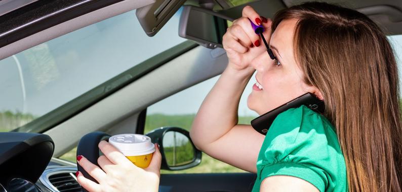 Distracted female driver applying makeup