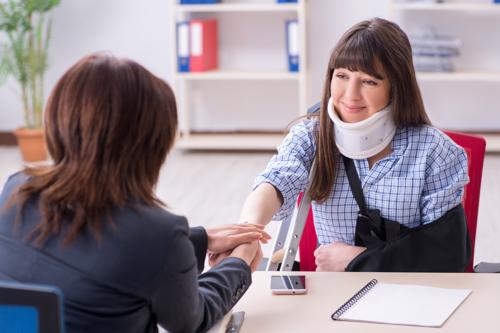 A woman meeting with a lawyer to discuss filing a compensation claim after being injured in a slip and fall accident.