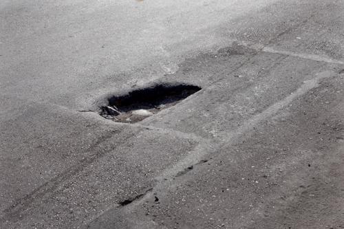 A pothole in a road, a hazard that can easily lead to a motorcycle accident.