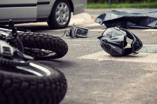 A motorcycle and helmet lying in a road after an accident with a car.