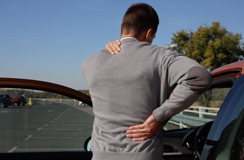 A man holding his back in pain after a car accident.
