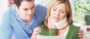 A woman with a neck injury looking at a settlement offer from an insurance company.