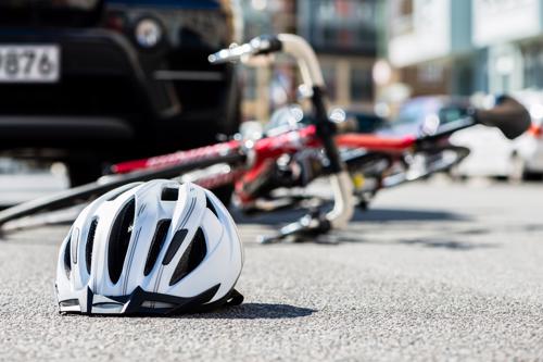 A bicycle and helmet lying in a street after an accident with a car.