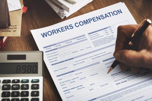 A person filling out a workers' compensation form after being injured on the job.