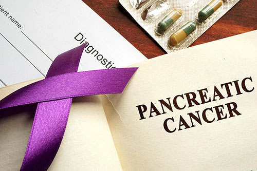 This image shows pancreatic cancer written on a page and purple awareness ribbon