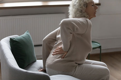 This image shows an older woman whose back hurts when she tries to stand.