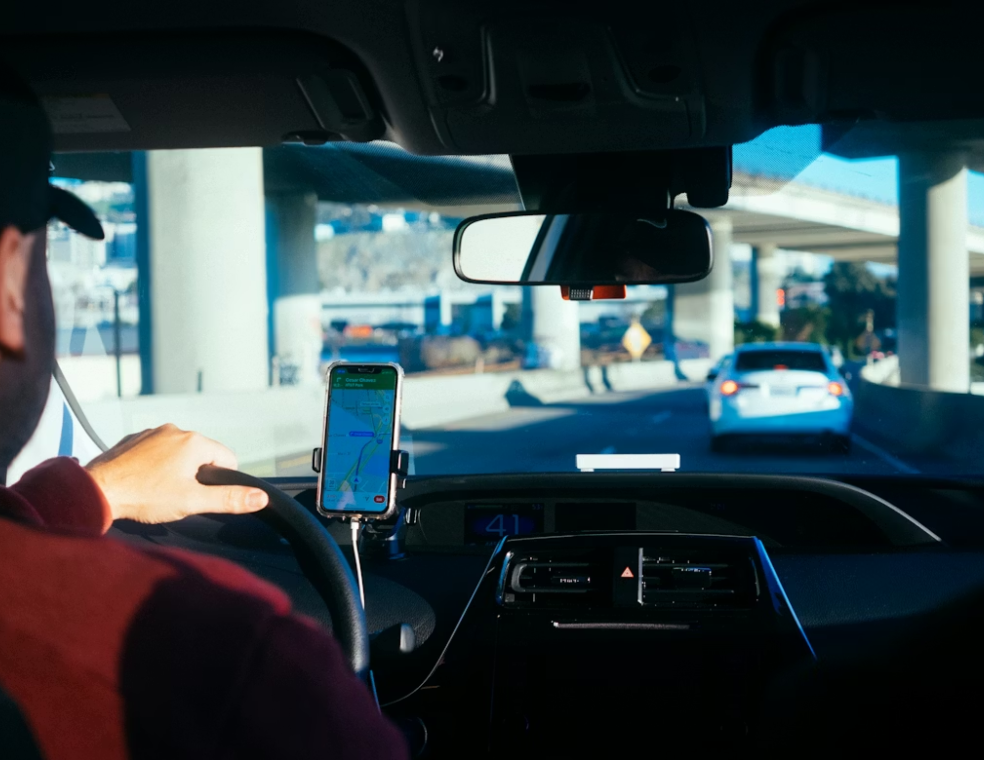 An Uber driver navigating a busy New York City road while looking at his GPS.