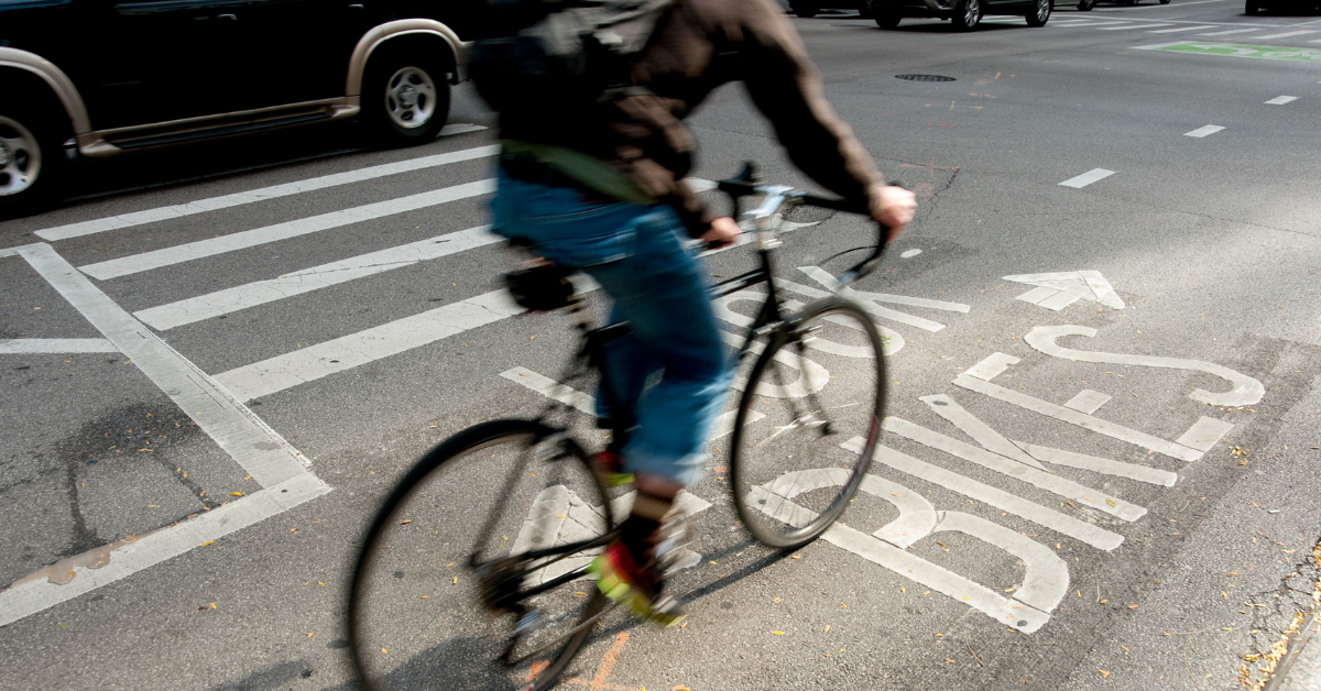 Bicyclist riding in a bike lane next to a car on a city street