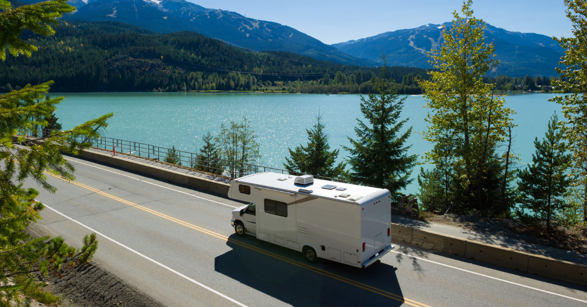 RV driving on a scenic road during summer travel.