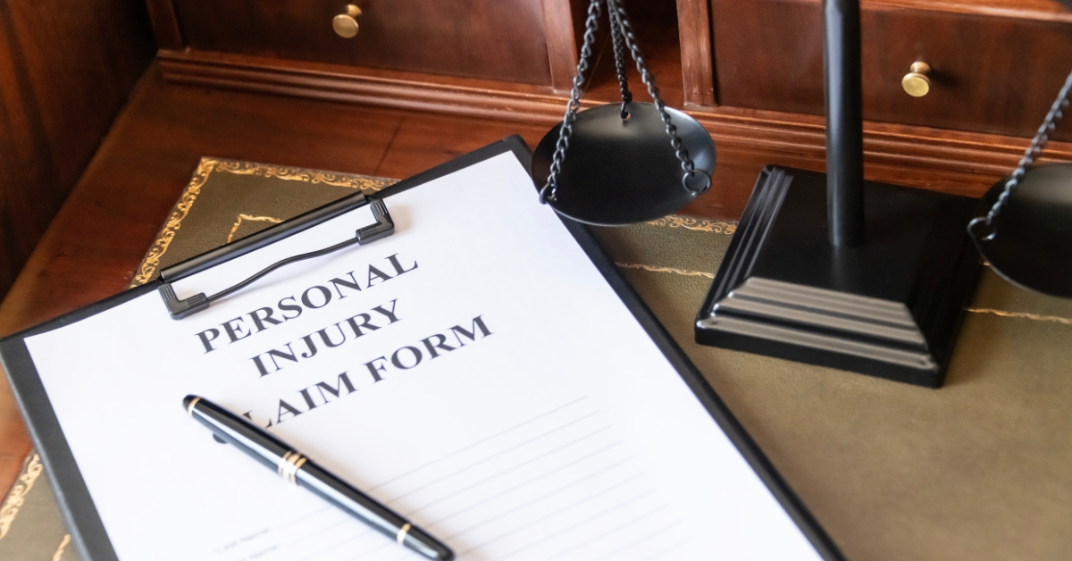 Personal injury claim form on a clipboard beside a pen and scales of justice, representing the importance of filing a claim.