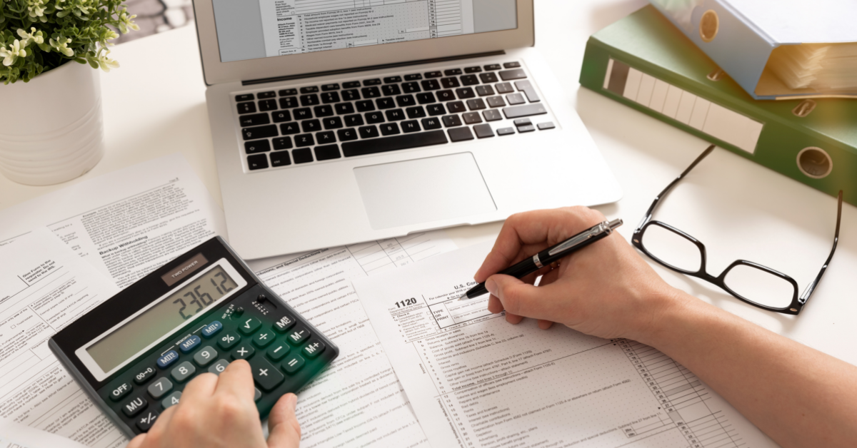 Person reviewing financial documents with a calculator and laptop while assessing lost wages and earning capacity.