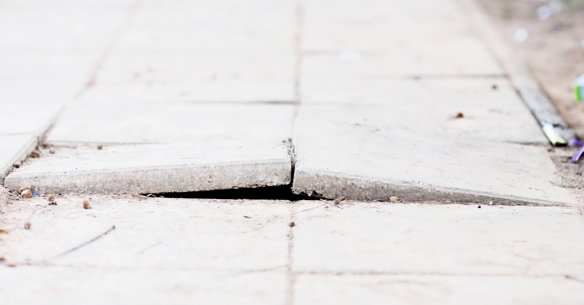 Raised and uneven concrete sidewalk slabs creating a tripping hazard.