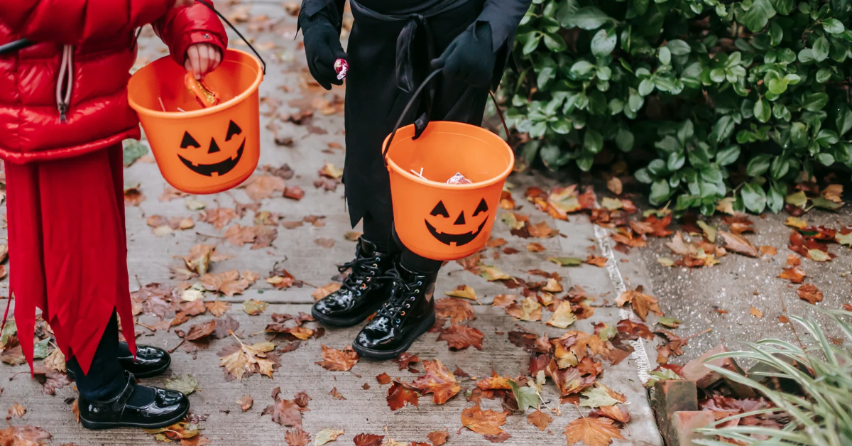 Children trick-or-treating in costumes on the sidewalk.
