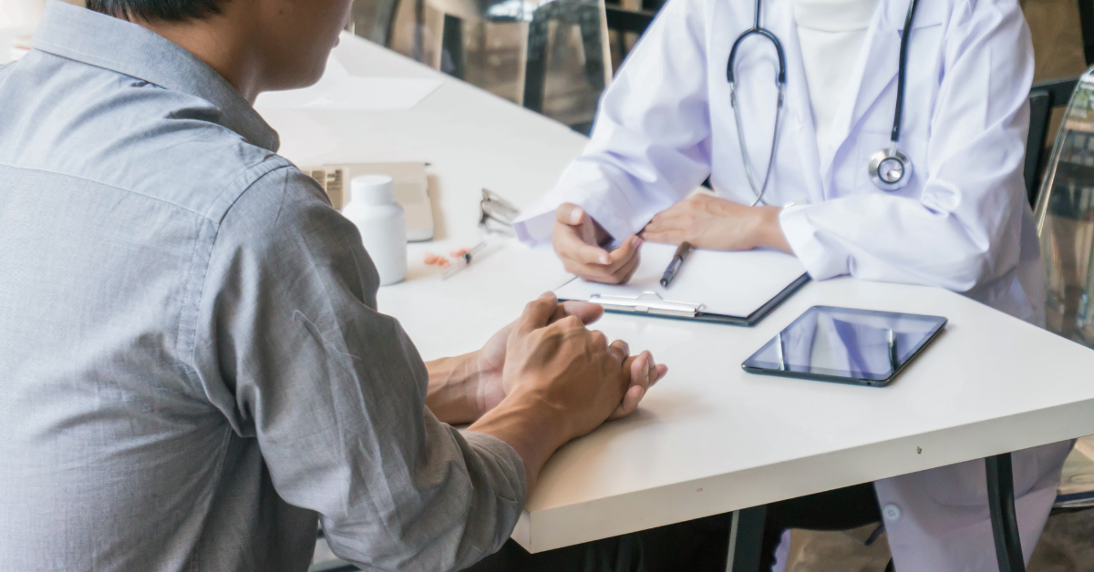 Alt Text: A person speaking with their medical provider at a table.