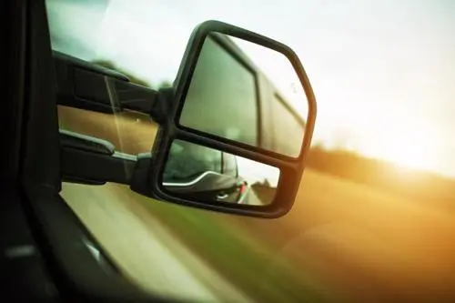 A close up photo of a rear-view mirror on a tractor-trailer.