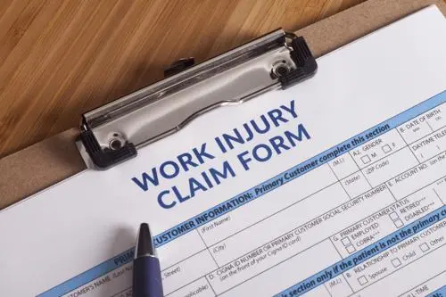 A work injury form and clipboard on a desk.