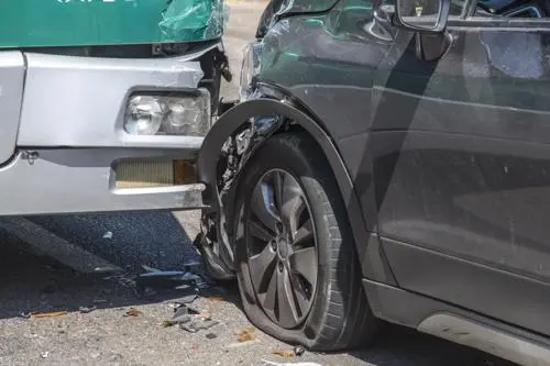 An accident between a large bus and a car.