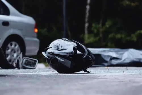 A motorcycle helmet lying in a road and a car in the background after an accident.
