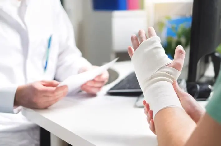 A person with a wrist injury from an accident meeting with a doctor.