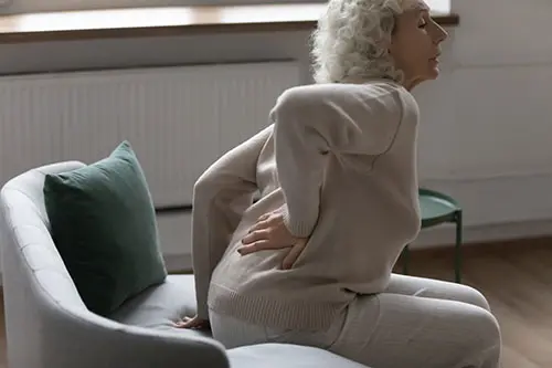 This image shows an older woman whose back hurts when she tries to stand.