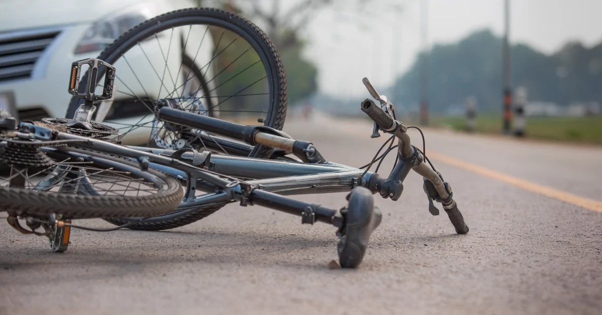 Bicycle lying on the road near a vehicle after a crash, representing the risks of dooring accidents for cyclists.