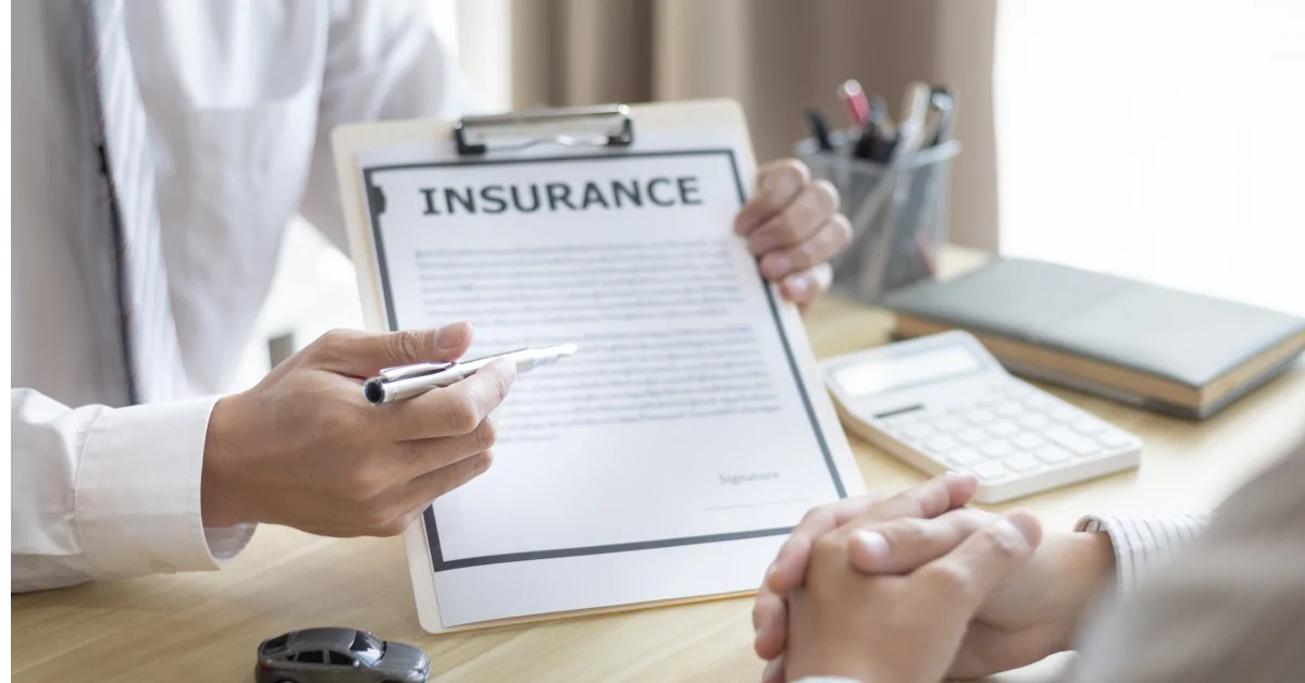 Insurance agent reviewing a policy with a client at a desk.